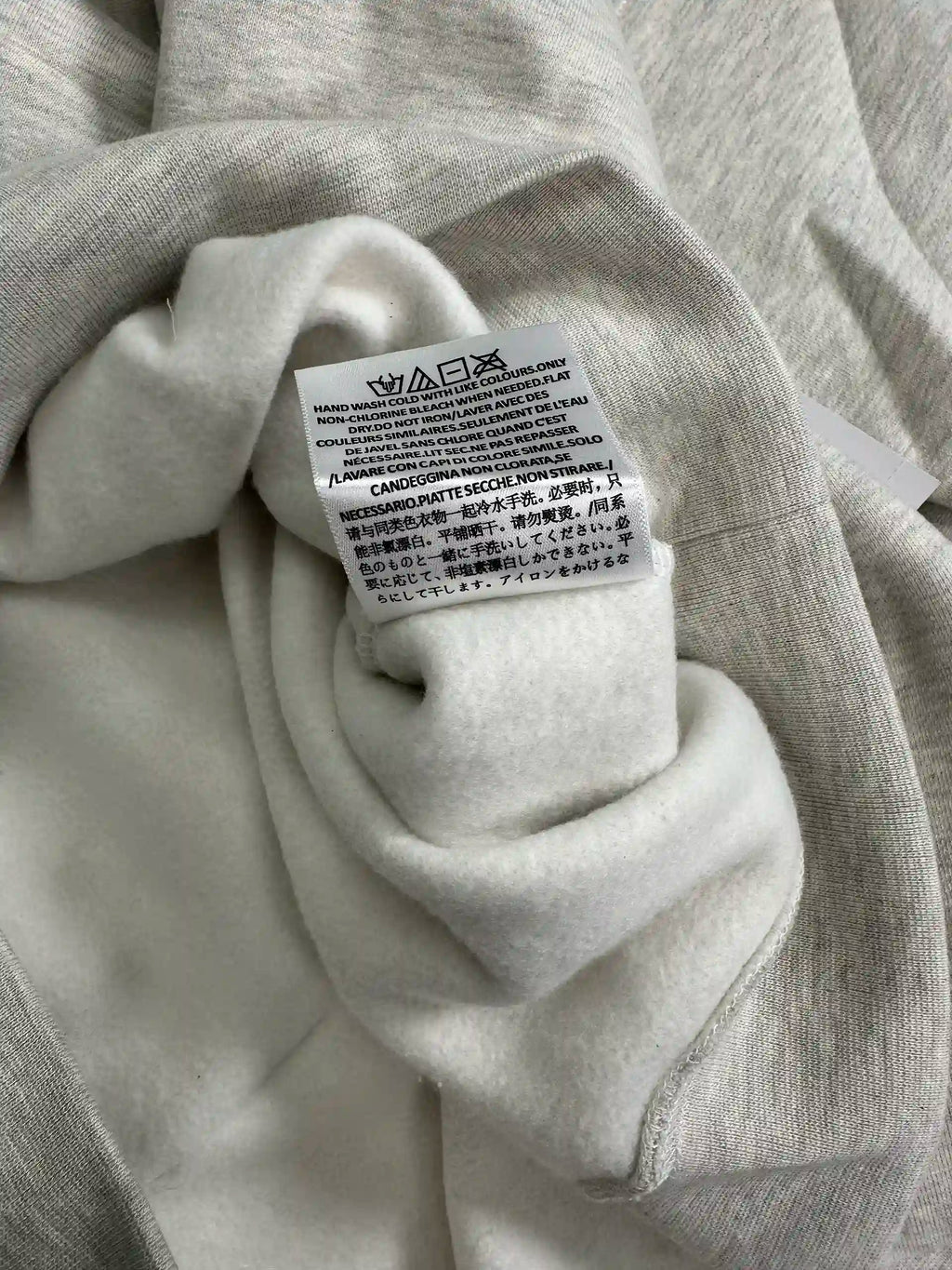 Interior care instructions label showing washing symbols on fleece hoodie