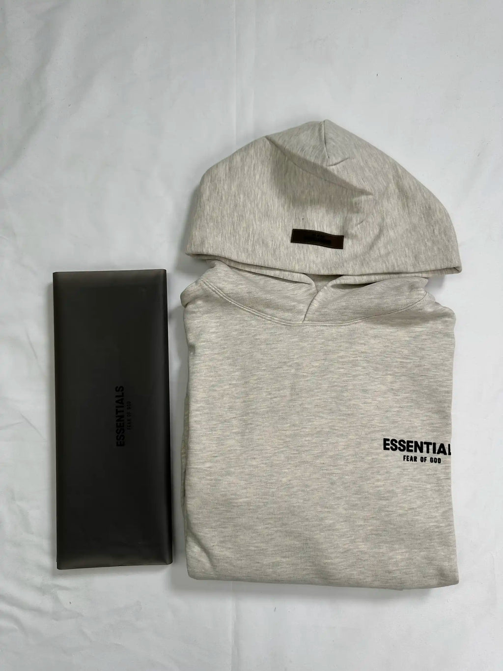 ESSENTIALS 2022 fleece hoodie in Light Oatmeal color, folded front view with original packaging