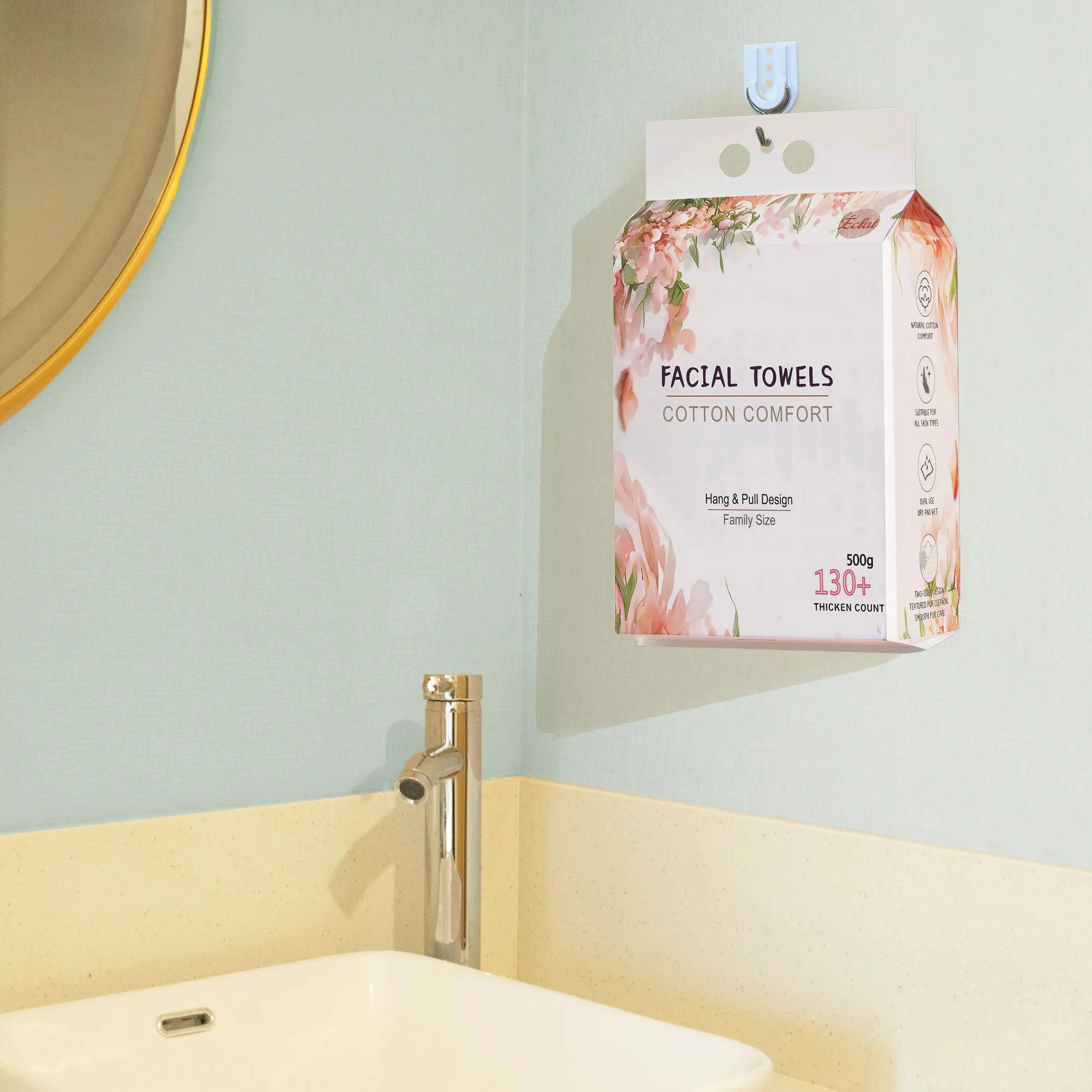 Wall-mounted disposable facial towel pack hanging in a bathroom for hygienic and space-saving storage, featuring 130+ cotton sheets and floral packaging.